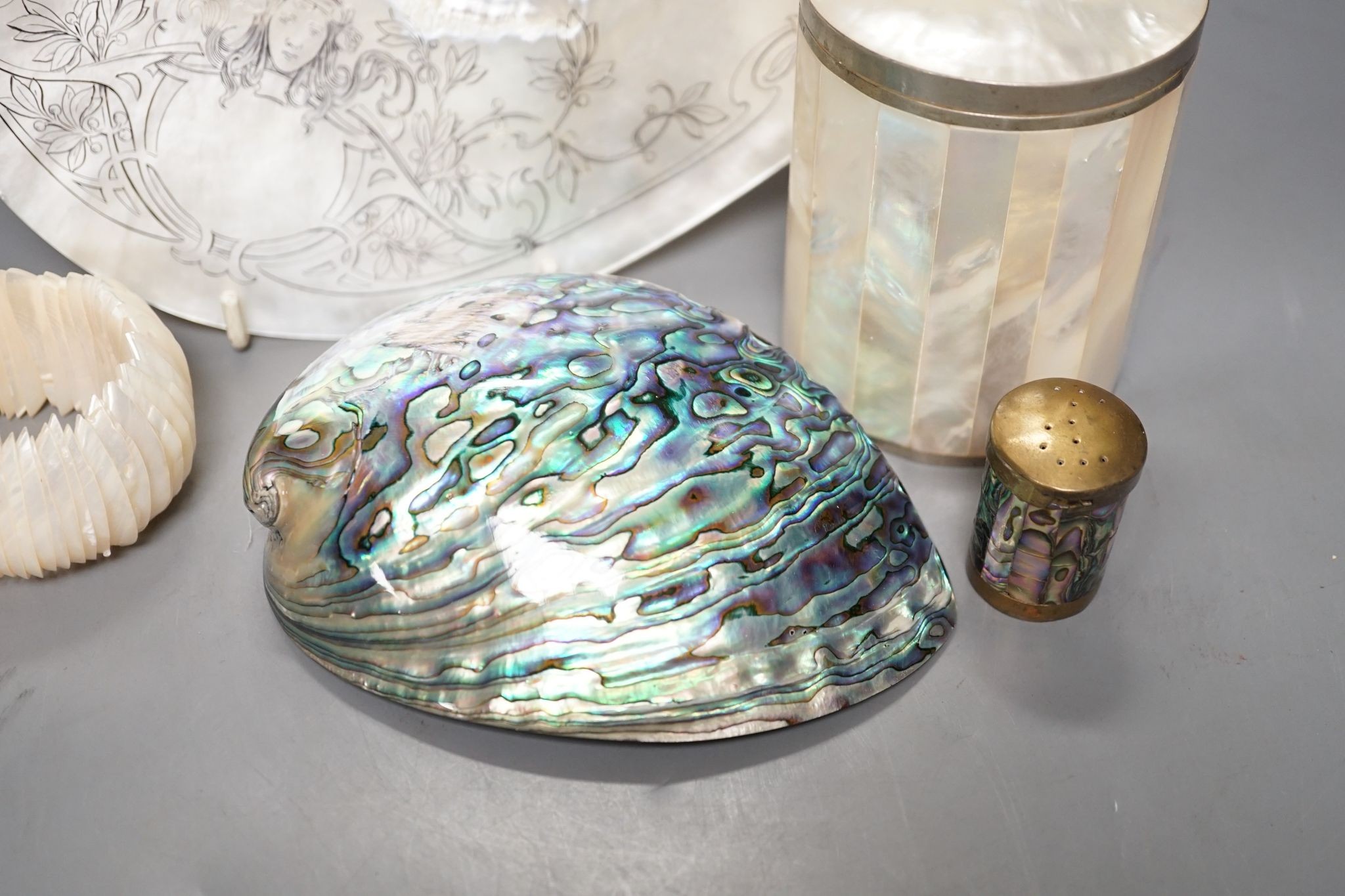 An engraved pearl shell, 22cm, a cylindrical box and bracelet, and two abalone shells